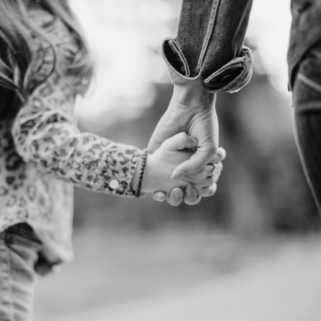 A mother and young child holding hands, representing the early attachment bonds that quietly shape our coping patterns, emotional responses, and sense of safety in adulthood